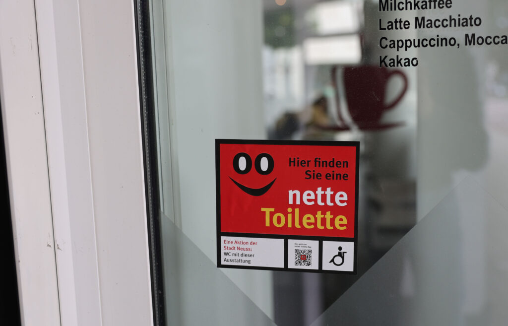 Ein Aufkleber "Nette Toilette" an einer Eingangstür